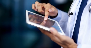 A doctor using a tablet device to read patient data analytics.