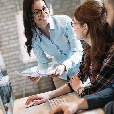 A woman with glasses talking to colleagues 