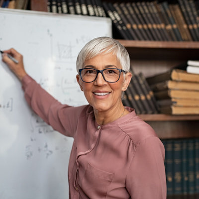 A woman smiling and writing on the whiteboard 