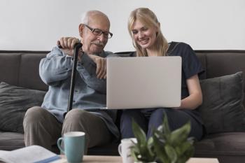 Domiciliary care worker showing laptop screen to gentleman