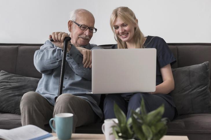 carer and old man using laptop