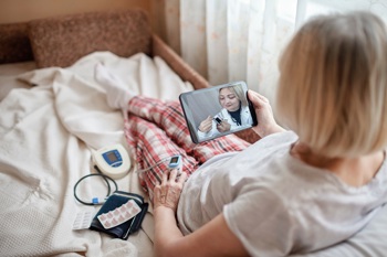 A patient using technology enabled care whilst sick in bed.