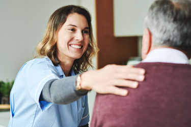 A nurse smiling with her arms around a man