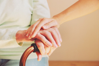 Elderly woman getting assistance by carer and walking stick to show complex needs are a challenge in brokerage