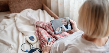 A patient at home on a virtual ward, being given instructions by a clinician on how to use her monitoring kit.