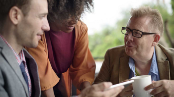 Two white men and a black woman smiling with each other