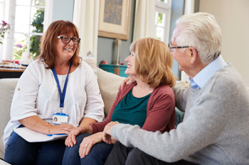 image of support worker chatting to a couple to help improve their health and wellbeing