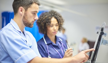 Two nurses evaluating patient data analytics.