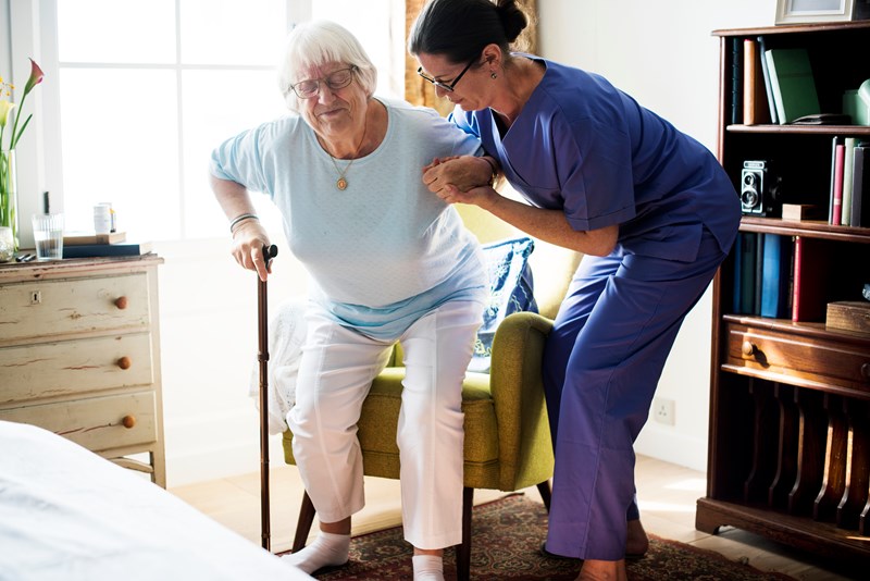 Carer helping elderly person to prevent her falling