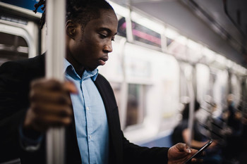 Young man on his phone whilst on the underground train