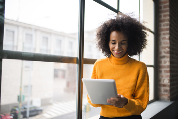 Lady using a laptop standing by a window