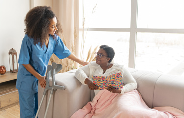 A black woman being comforted by a black female nurse