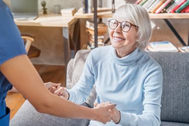 An elderly white woman holding hands with a nurse