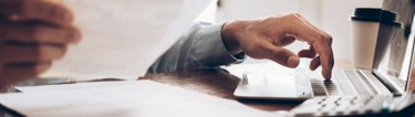 A man typing out something off of a piece of paper.