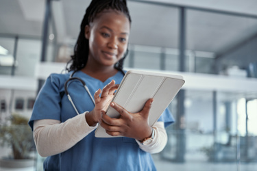 A black female nurse looking at an electronic tablet