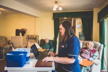 A female nurse in her uniform using a laptop