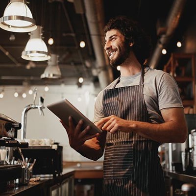 A waiter smiling holding a tablet 