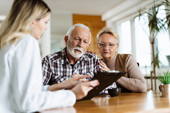 An elderly couple reading something off of a young woman's clipboard