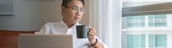 Man drinking coffee in the office while researching cloud payroll software