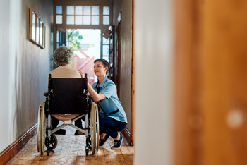 An elderly woman in a wheelchair talking with a carer.