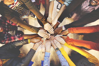 Students with their hands in a pile - motivational action to encourage performance.