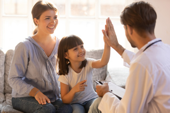 An image of a child smiling and high fiving a support worker to show children's mental health is important 