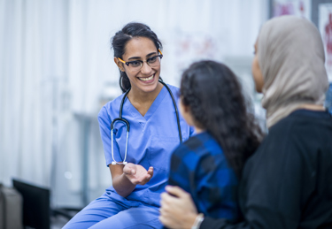 A woman with a child on her lap talking to a nurse