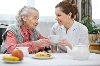 Care worker giving tea to client as part of person-centered care